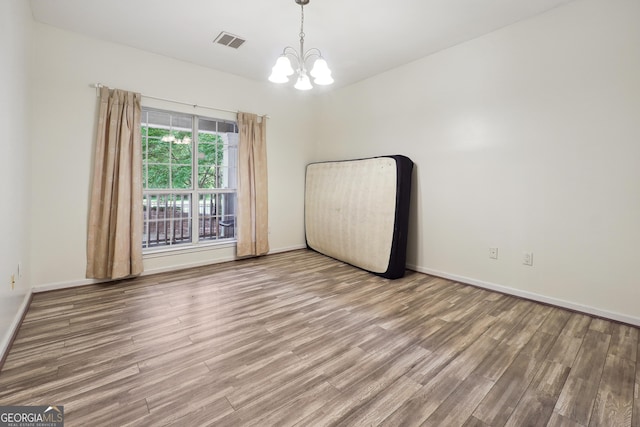 unfurnished room with hardwood / wood-style flooring and a notable chandelier