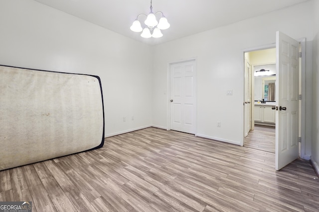 unfurnished bedroom with light hardwood / wood-style flooring and a notable chandelier