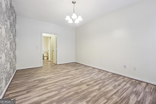 empty room featuring a chandelier and light hardwood / wood-style flooring