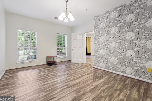 unfurnished room with hardwood / wood-style flooring and a chandelier