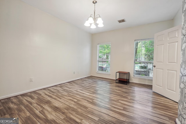 unfurnished room with an inviting chandelier and hardwood / wood-style floors