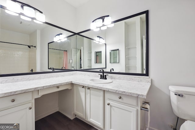 bathroom featuring toilet, vanity, wood-type flooring, and a shower