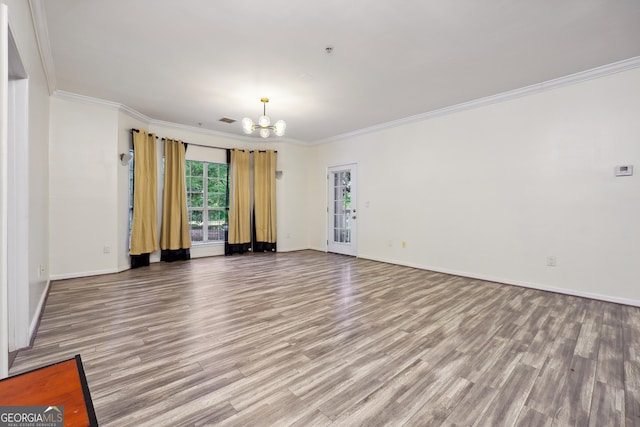 empty room featuring an inviting chandelier, ornamental molding, and hardwood / wood-style flooring