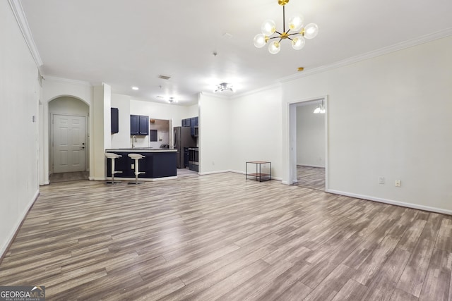 living room featuring ornamental molding, a notable chandelier, and light wood-type flooring