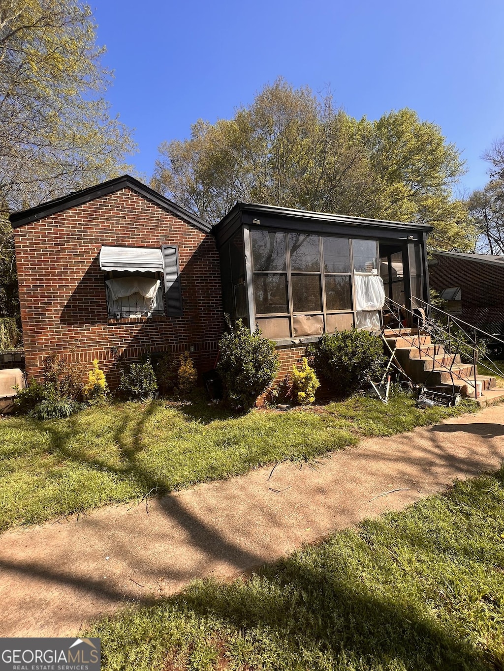 view of side of home featuring a sunroom and a yard