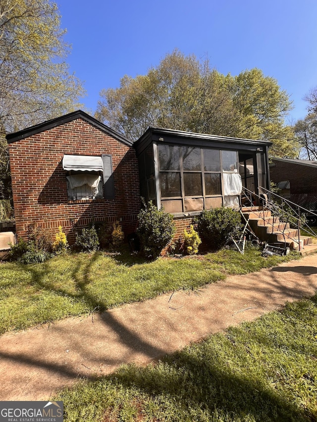 view of side of home featuring a sunroom and a yard