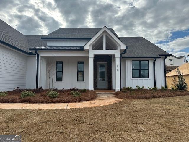 view of front of home featuring a front lawn, board and batten siding, and a shingled roof