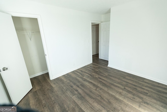 unfurnished bedroom featuring a closet and dark hardwood / wood-style flooring