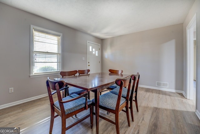 dining room featuring a textured ceiling and light hardwood / wood-style floors