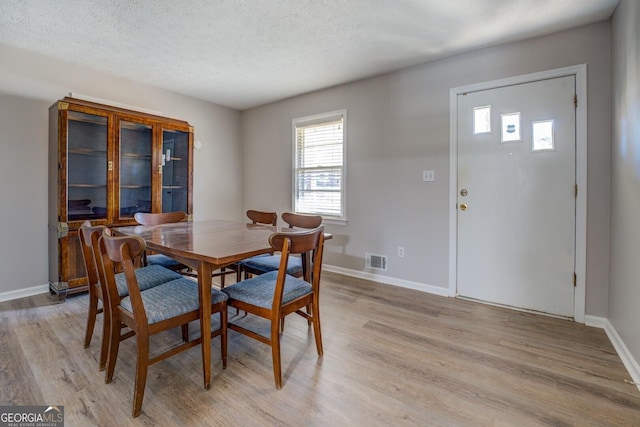 dining room with a textured ceiling and light hardwood / wood-style flooring