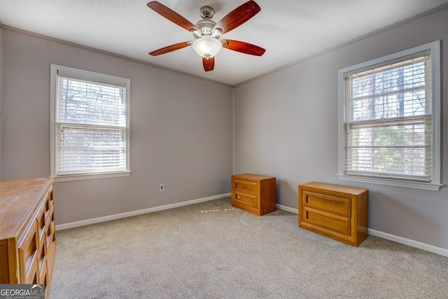 carpeted spare room with ceiling fan, plenty of natural light, and ornamental molding