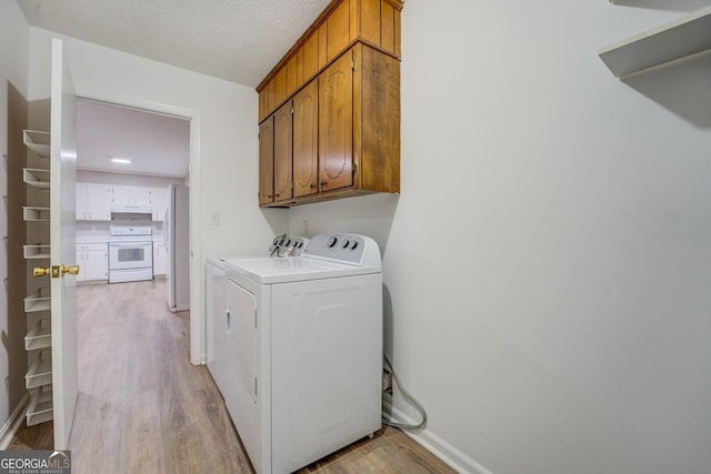 laundry room with cabinets, a textured ceiling, light hardwood / wood-style flooring, and independent washer and dryer