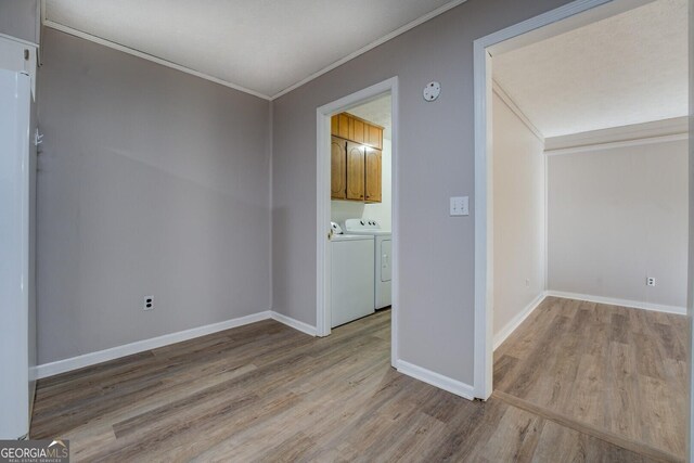 unfurnished room featuring separate washer and dryer, ornamental molding, and light hardwood / wood-style floors