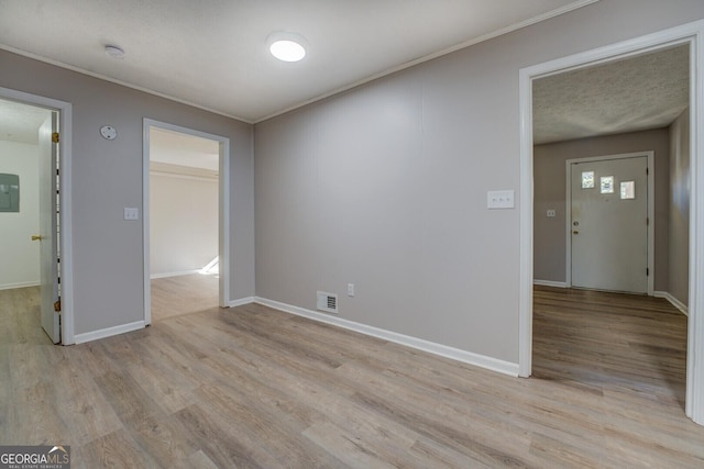 spare room featuring electric panel and light hardwood / wood-style flooring