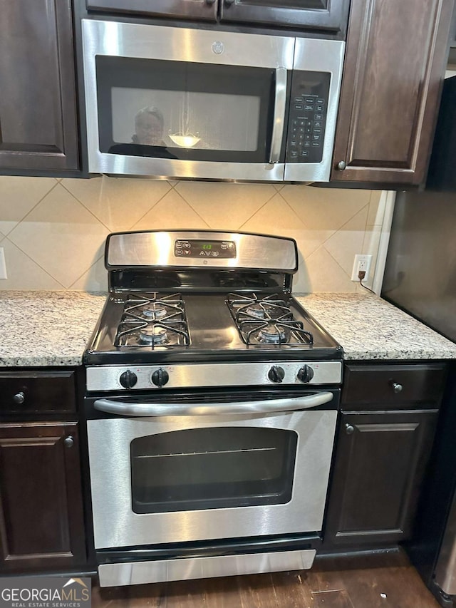 kitchen with light stone countertops, backsplash, and appliances with stainless steel finishes