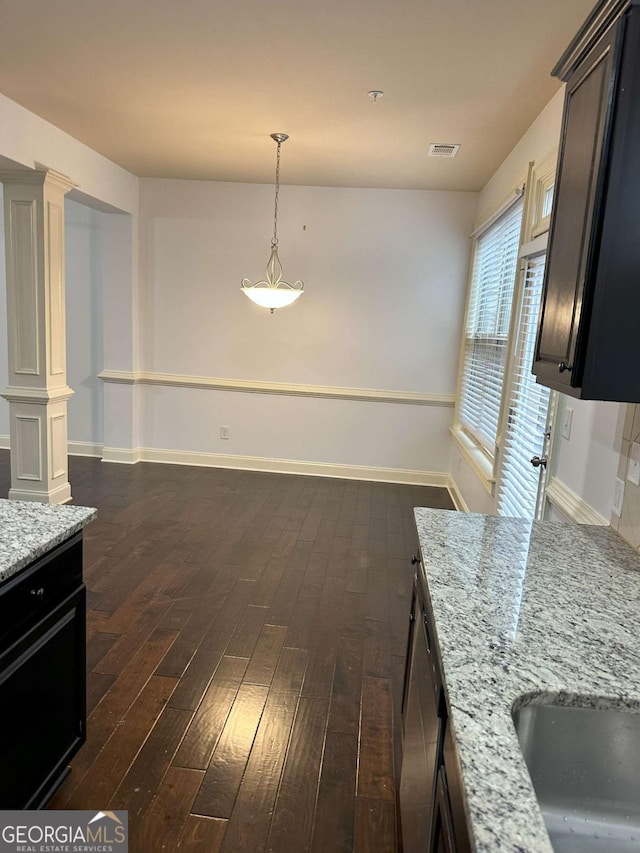 kitchen with dishwashing machine, dark hardwood / wood-style floors, light stone countertops, and dark brown cabinetry