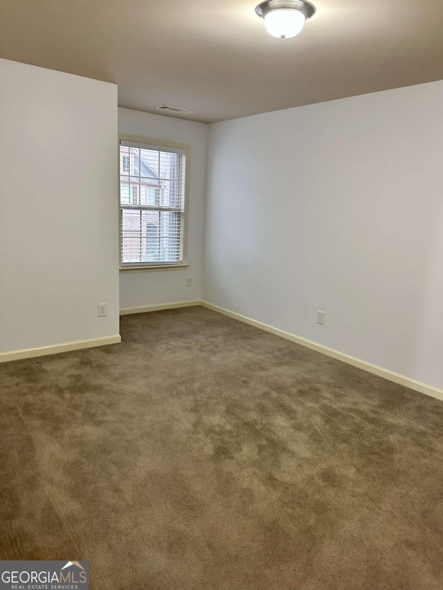 spare room with dark carpet