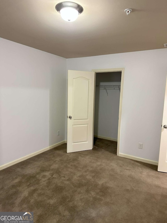 unfurnished bedroom with a closet and dark colored carpet