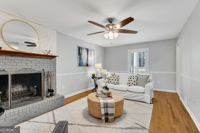 living room featuring ceiling fan, hardwood / wood-style floors, and a brick fireplace