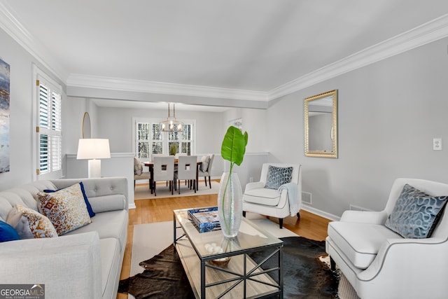 living room featuring hardwood / wood-style flooring, ornamental molding, and a notable chandelier