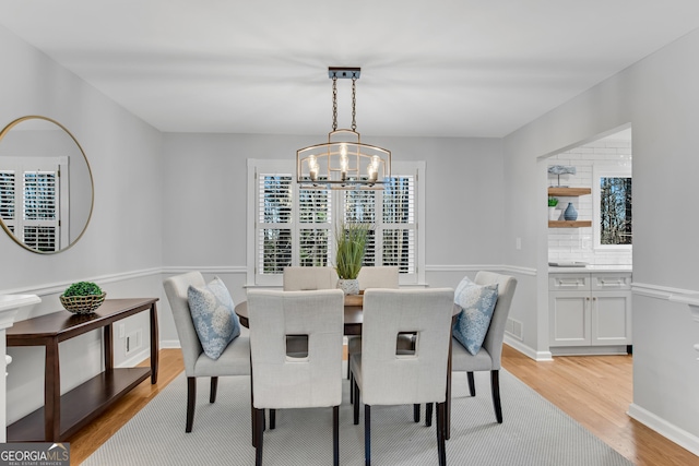 dining space with light hardwood / wood-style floors and a notable chandelier