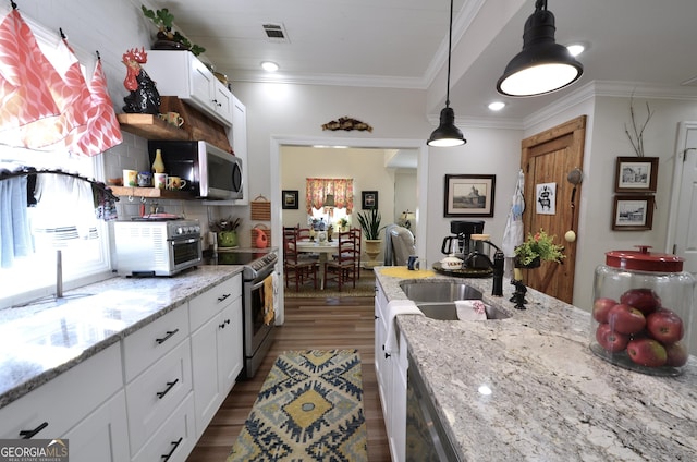 kitchen with pendant lighting, sink, appliances with stainless steel finishes, white cabinets, and light stone counters