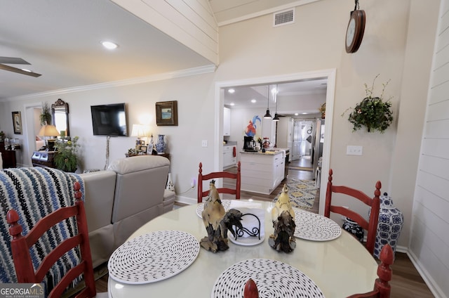 dining room with ceiling fan, wood-type flooring, and crown molding