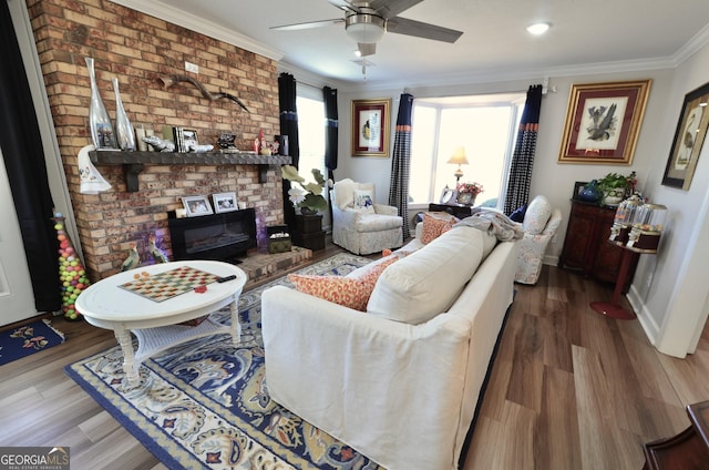 living room featuring ceiling fan, crown molding, a fireplace, and wood-type flooring