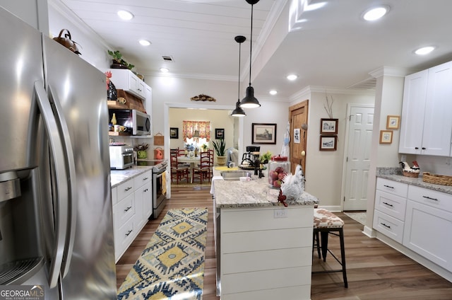 kitchen with white cabinets, appliances with stainless steel finishes, a kitchen island, a kitchen breakfast bar, and sink