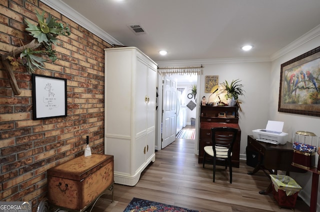 hall with brick wall, crown molding, and hardwood / wood-style floors