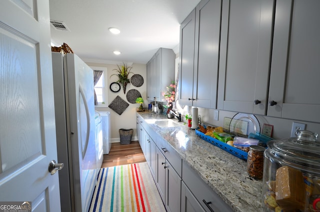 kitchen featuring light stone countertops, sink, gray cabinetry, and white fridge