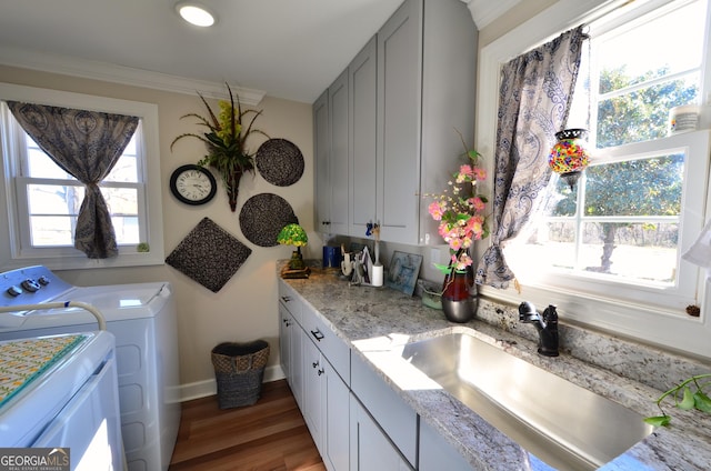 laundry room with sink, a healthy amount of sunlight, dark wood-type flooring, separate washer and dryer, and cabinets