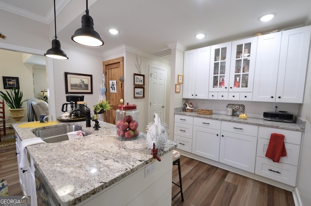 kitchen with an island with sink, dark hardwood / wood-style floors, hanging light fixtures, white cabinets, and sink