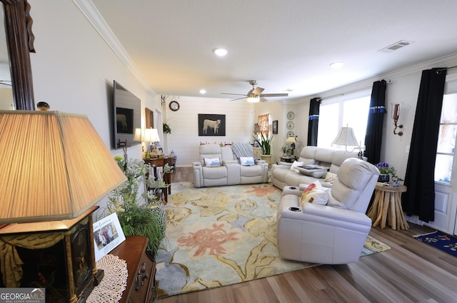 living room featuring hardwood / wood-style flooring, ornamental molding, and ceiling fan