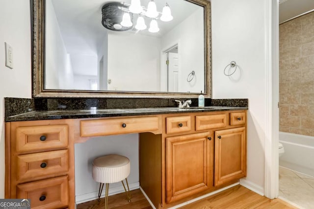 full bathroom featuring toilet, vanity, wood-type flooring, and tiled shower / bath