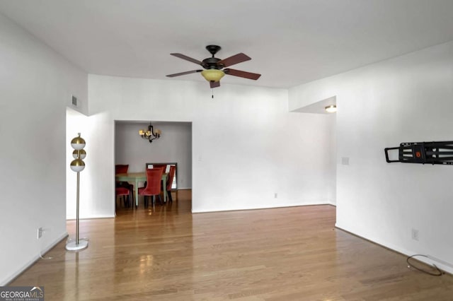 unfurnished room with ceiling fan with notable chandelier and hardwood / wood-style floors