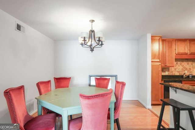 dining space featuring light wood-type flooring, sink, and a notable chandelier