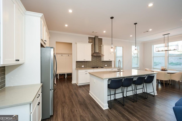 kitchen featuring wall chimney exhaust hood, sink, white cabinets, and stainless steel fridge