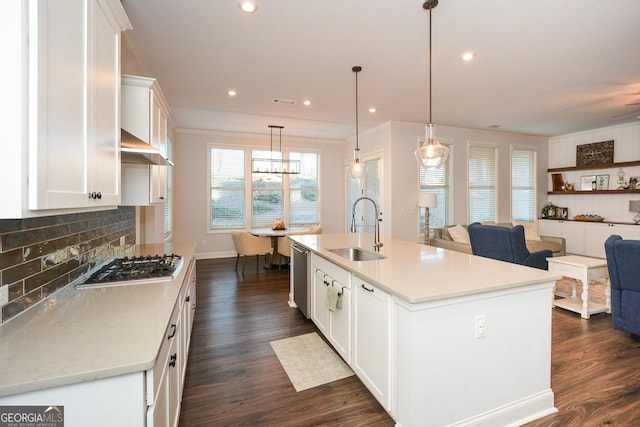 kitchen with appliances with stainless steel finishes, a kitchen island with sink, sink, white cabinets, and pendant lighting