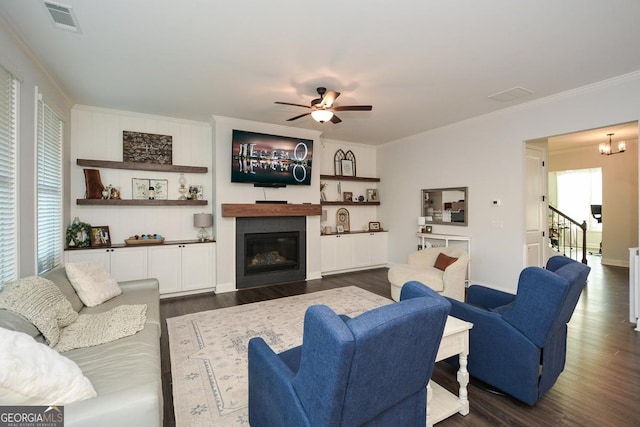 living room featuring crown molding, plenty of natural light, ceiling fan with notable chandelier, and dark hardwood / wood-style floors