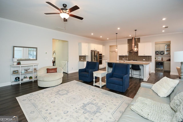 living room featuring beverage cooler, sink, dark hardwood / wood-style floors, ornamental molding, and ceiling fan