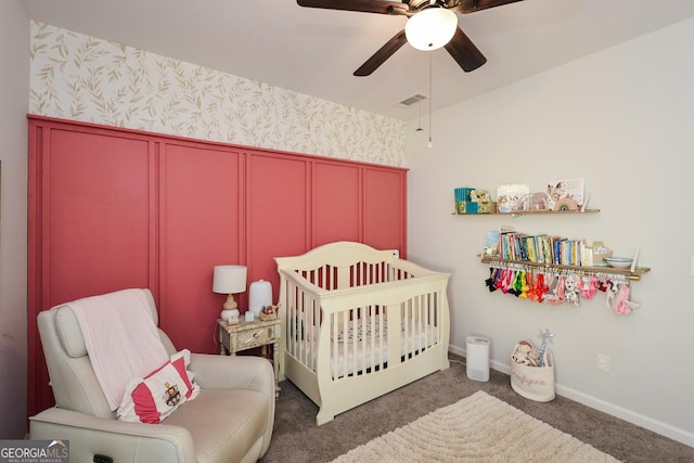 carpeted bedroom with ceiling fan and a crib