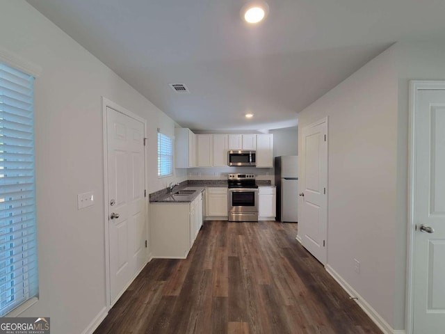 kitchen with dark wood-type flooring, appliances with stainless steel finishes, white cabinets, and sink