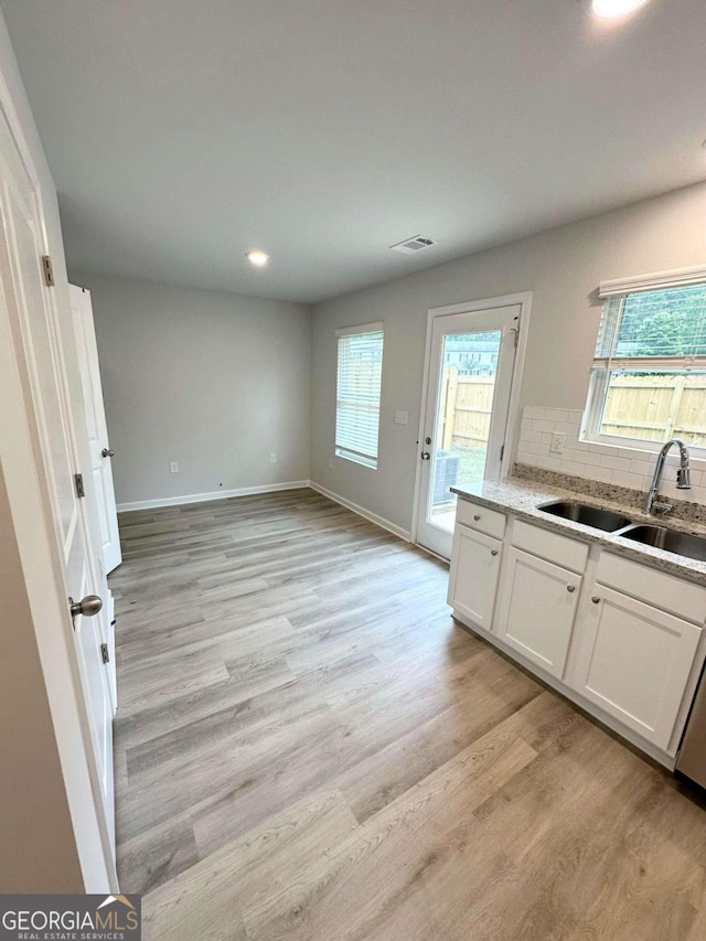 kitchen featuring sink, a wealth of natural light, white cabinets, and light wood-type flooring