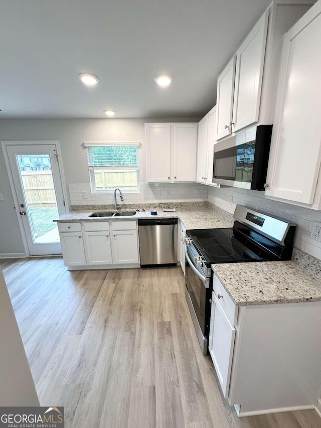 kitchen with a wealth of natural light, appliances with stainless steel finishes, sink, and white cabinetry