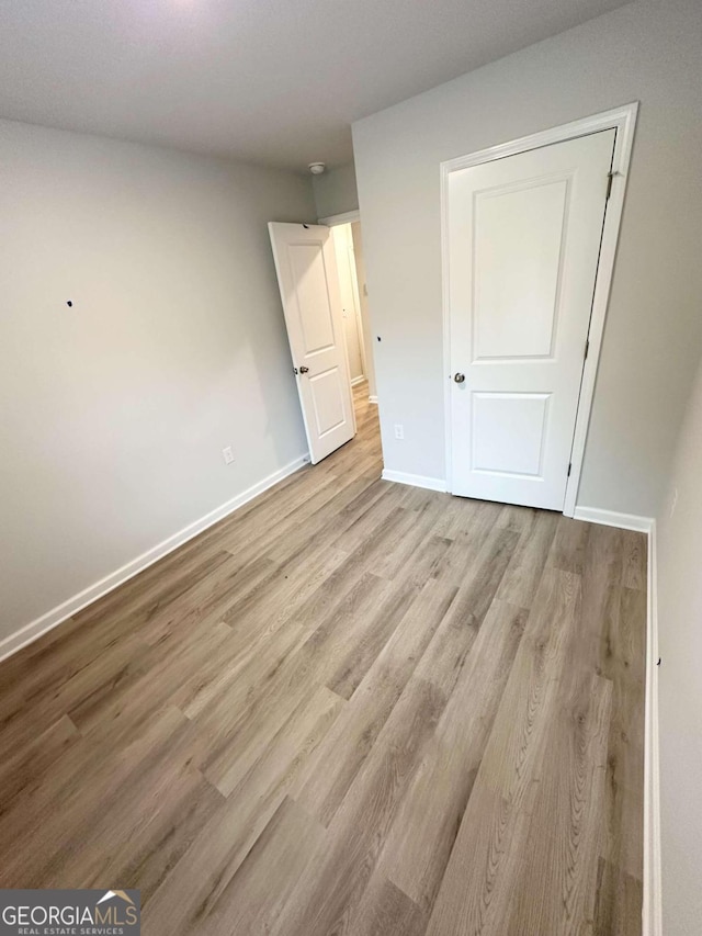 unfurnished bedroom featuring light wood-type flooring and a closet