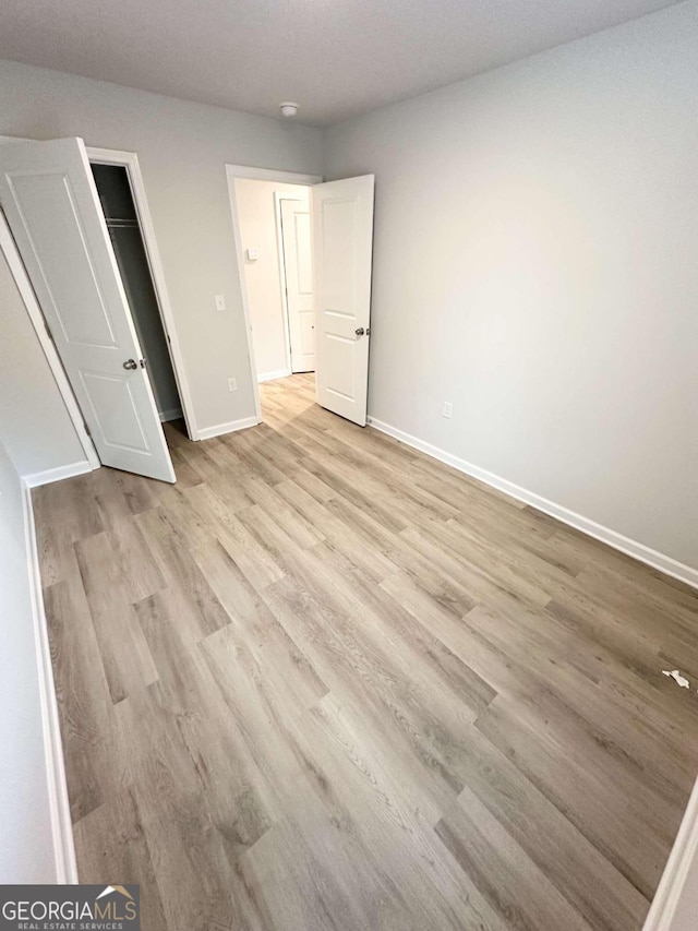 unfurnished bedroom with a closet and light wood-type flooring