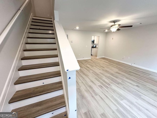 stairs featuring ceiling fan and hardwood / wood-style floors