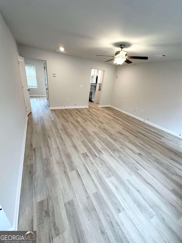 empty room with ceiling fan and light hardwood / wood-style flooring