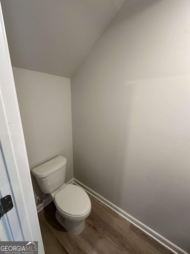 bathroom with hardwood / wood-style flooring, toilet, and vaulted ceiling